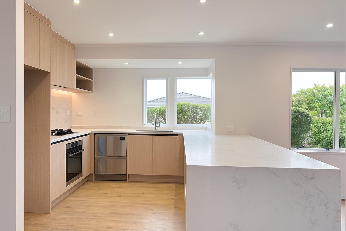 Modern open-plan kitchen in West Auckland with stone waterfall island and oak cabinetry.
