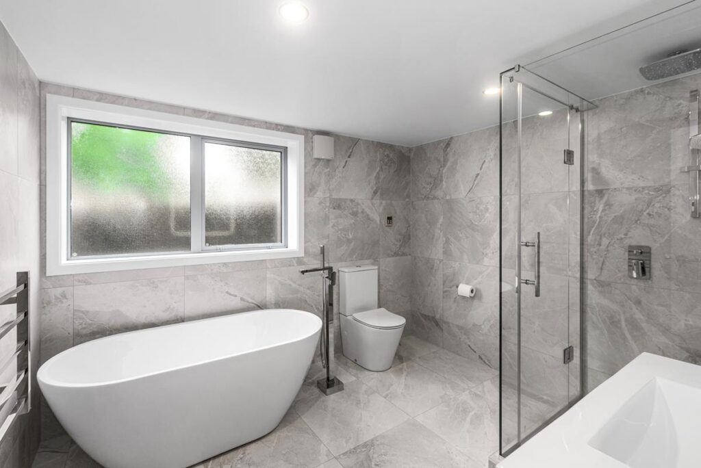 Marble-tiled walk-in shower with modern fittings in the family bathroom.