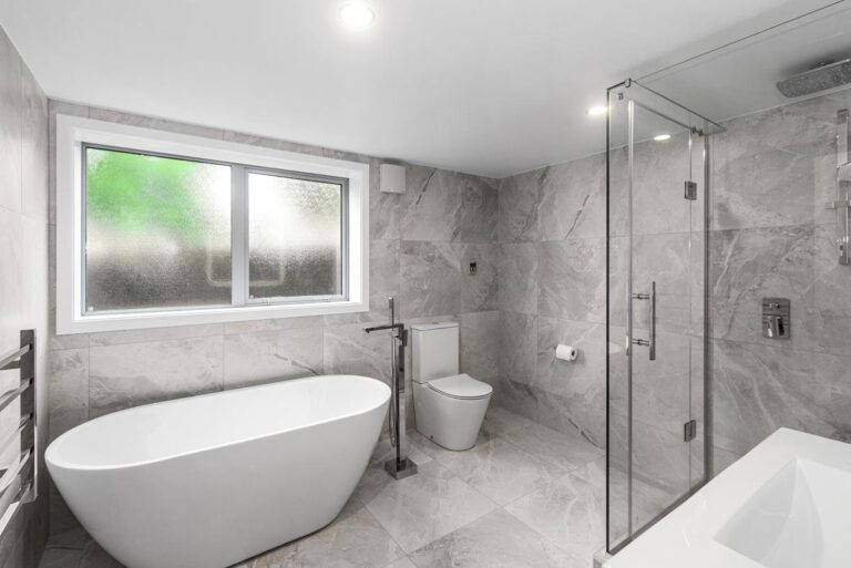 Marble-tiled walk-in shower with modern fittings in the family bathroom.
