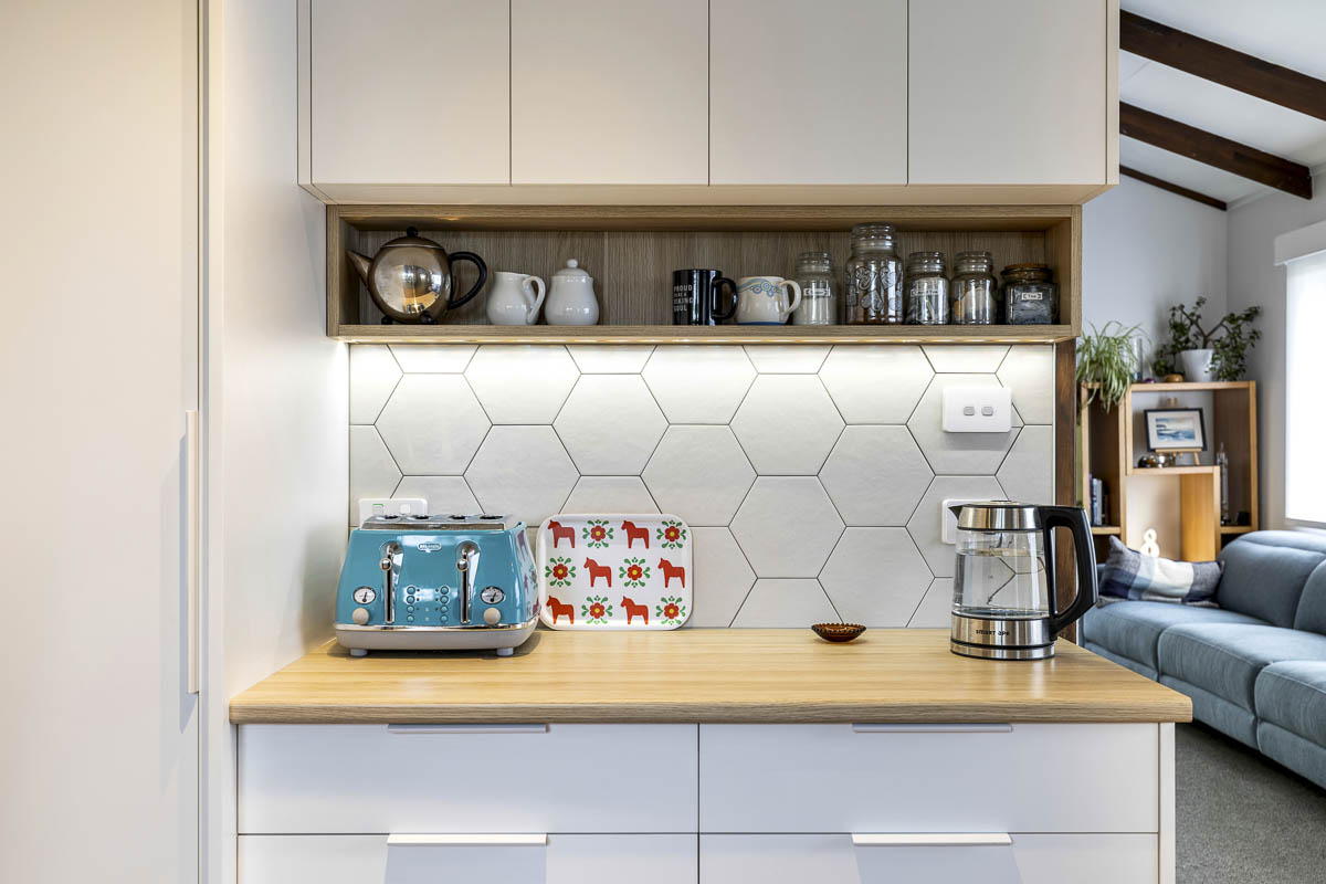 Lynfield white kitchen with floating timber shelf and gunmetal tapware