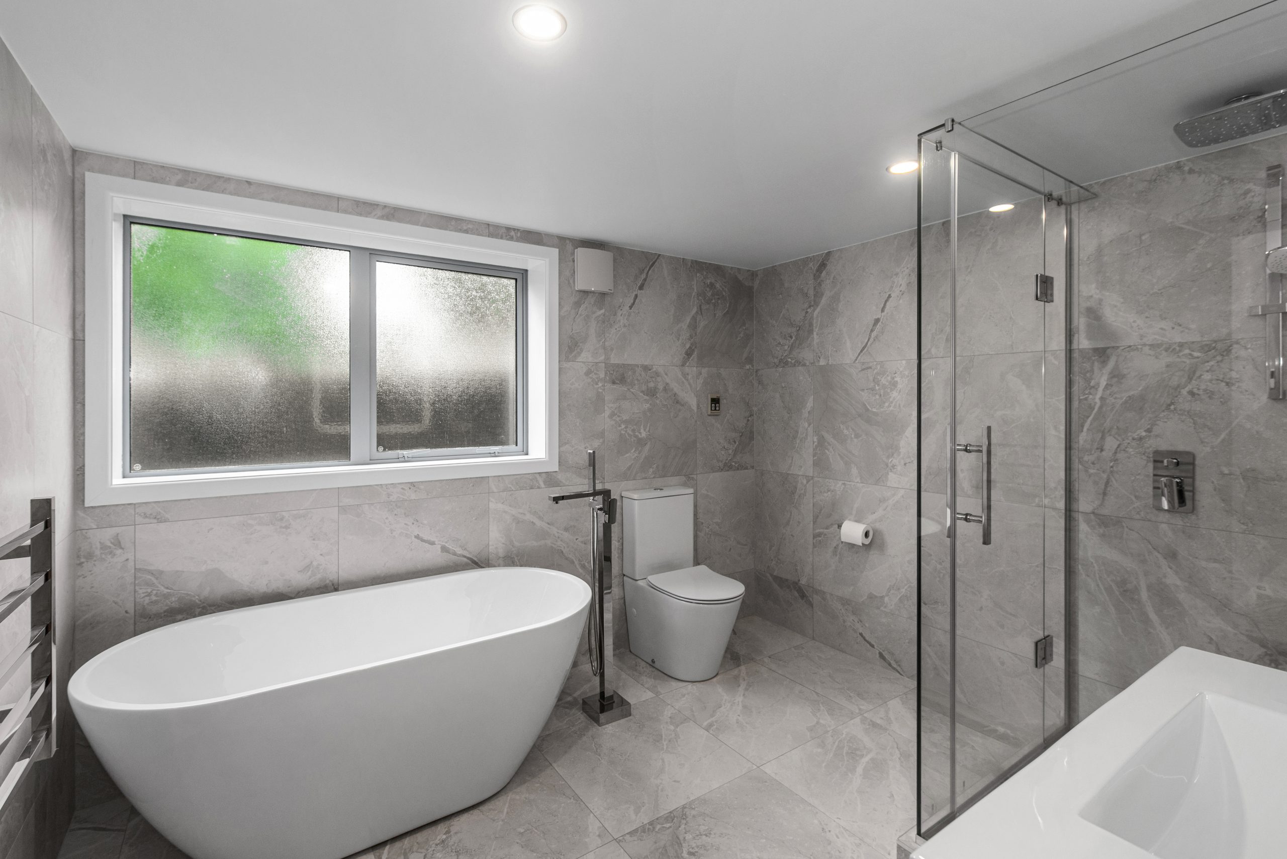 Master suite ensuite addition with freestanding bath, walk-in shower and grey marble tiles — Auckland renovation by Add Value Renovations