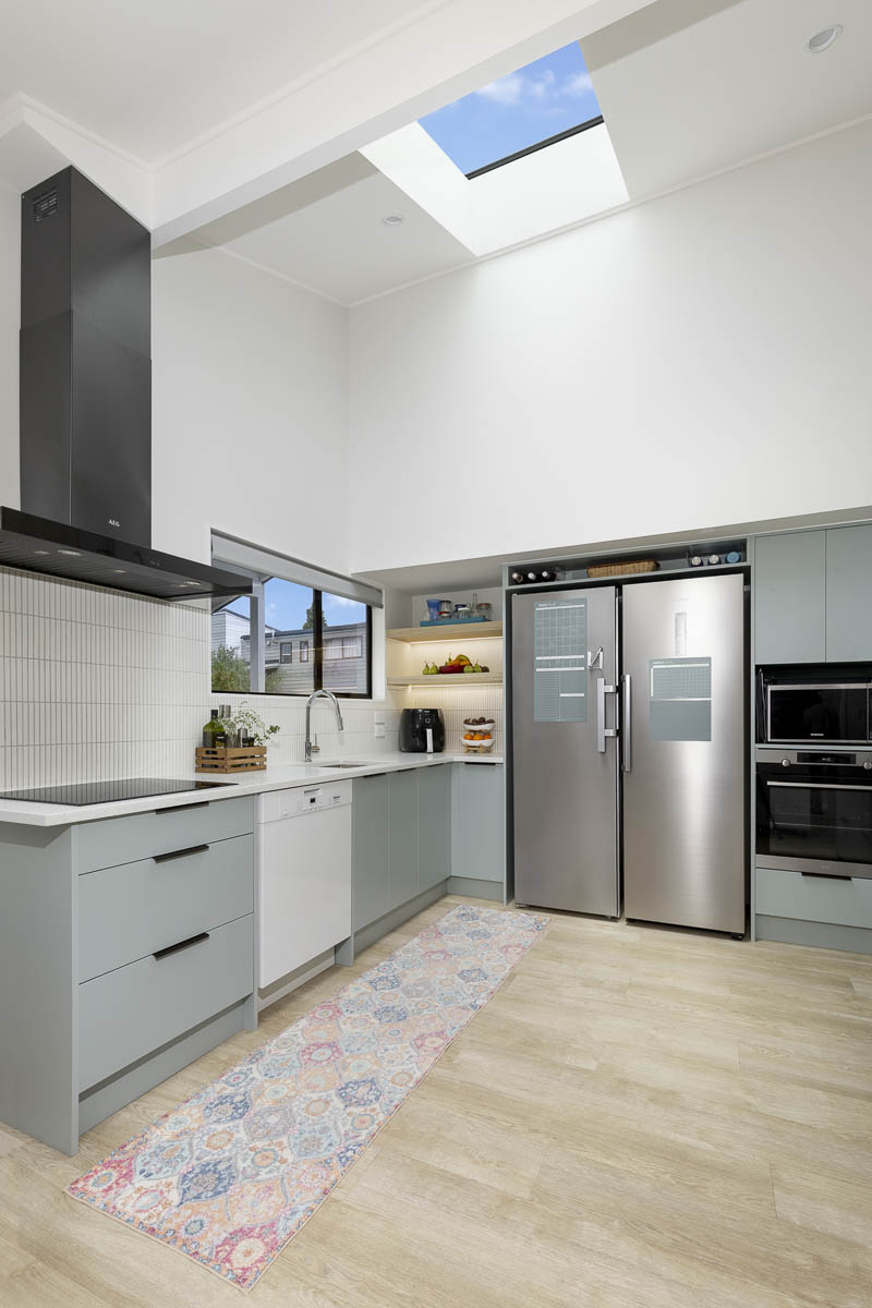 Open-plan kitchen renovation Auckland with double-height ceiling, skylight and island