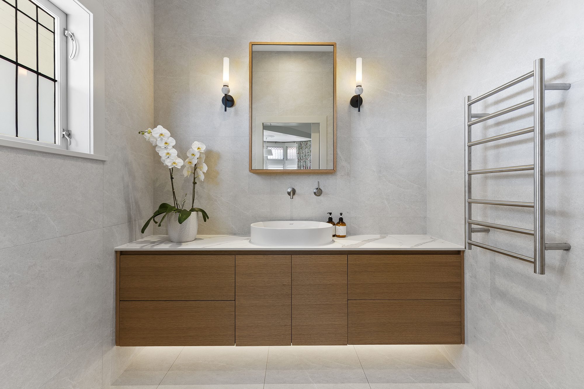 Remuera bungalow ensuite by Add Value Renovations — floating veneer vanity, stone top, twin wall lights and custom mirror cabinet