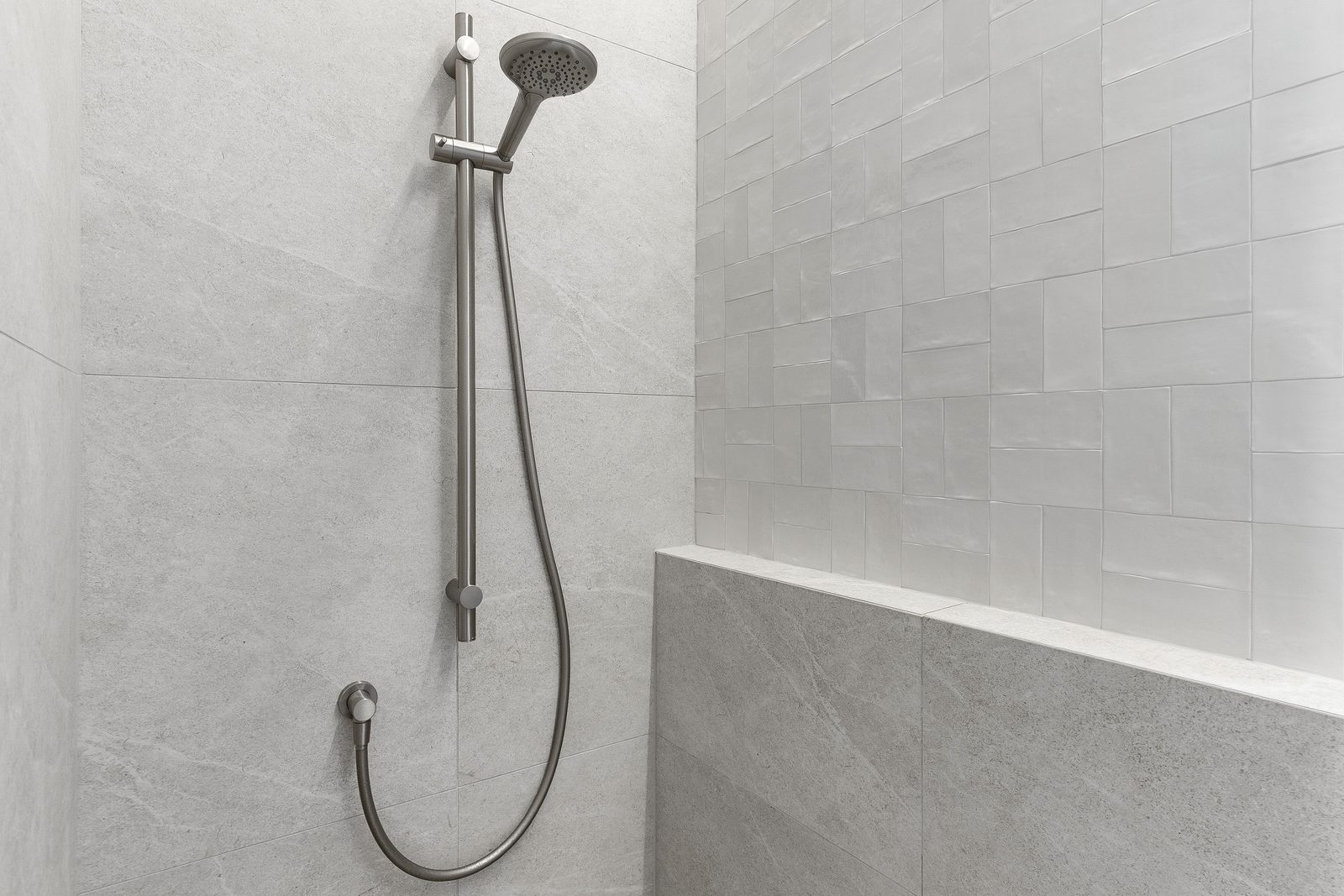 Remuera ensuite after — walk-in shower with handheld rail, grey stone tile and Fez White feature wall over a tiled bench