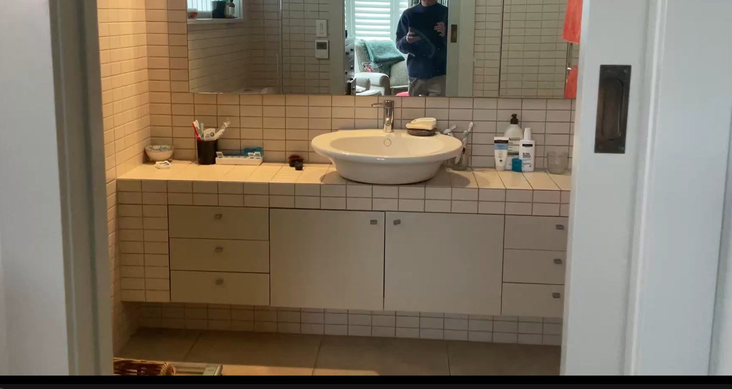 Remuera ensuite before renovation — dated tiled vanity top, laminate cabinetry and drop-in basin