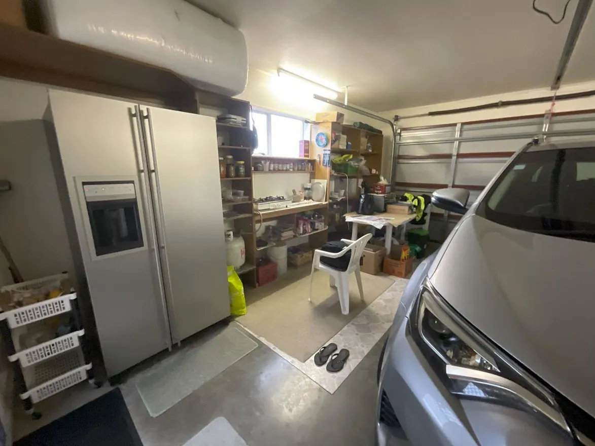 West Auckland garage used as overflow kitchen with gas bottles and open shelving.